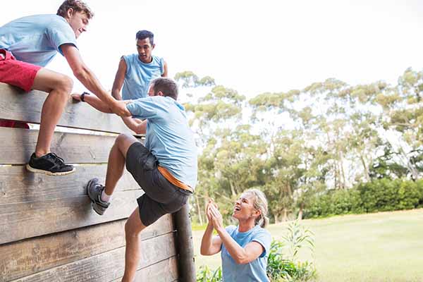 Team building - group climbing over an assault course wall
